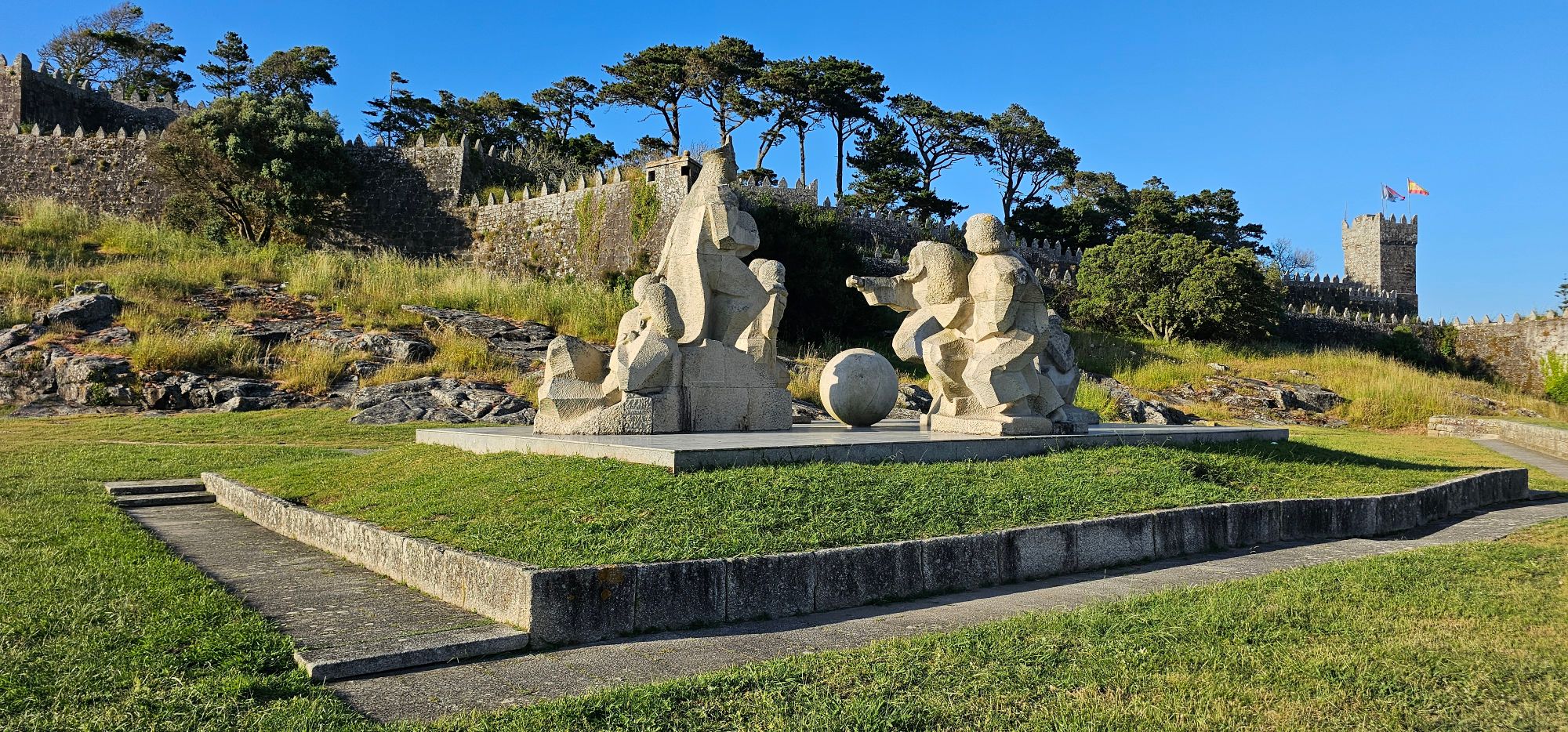 El Monumento Encuentro entre los Dos Mundos . Este conjunto escultórico, ubicado en el corazón del Parque de la Palma y junto a la impresionante muralla del Castillo de Monterreal, es un homenaje al descubrimiento del Nuevo Mundo y un símbolo de la conexión histórica y emocional entre Galicia y América. Baiona, Rutas en Moto, Guía de Mototurismo, Pontevedra, Galicia | SUKI ON THE ROAD